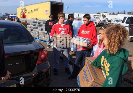 Oceanport, N.J., Nov. 6, 2012   Volunteers from local schools help load food and water for storm survivors at a distribution area organized by the Manmouth County Sheriff Department. FEMA is organizing relief efforts with varies organizations. New Jersey Hurricane Sandy. Photographs Relating to Disasters and Emergency Management Programs, Activities, and Officials Stock Photo