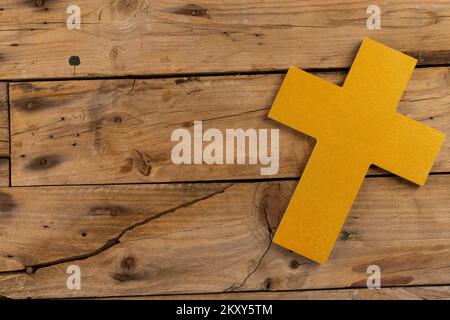 Composition of yellow cross and copy space on wooden background Stock Photo