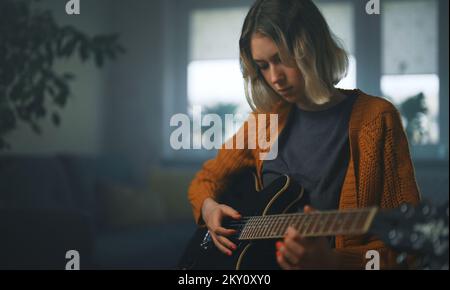 Teenage girl learning to play semi-acoustic guitar. Stock Photo