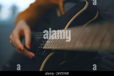 Girl playing semi-acoustic guitar at home. Stock Photo