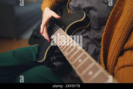 Girl playing semi-acoustic guitar at home. Stock Photo