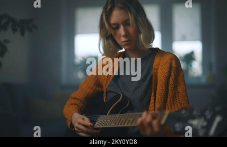 Teenage girl learning to play semi-acoustic guitar. Stock Photo