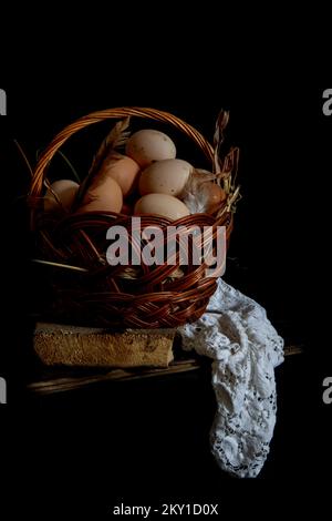 Chicken eggs in a wicker basket on a dark background Stock Photo