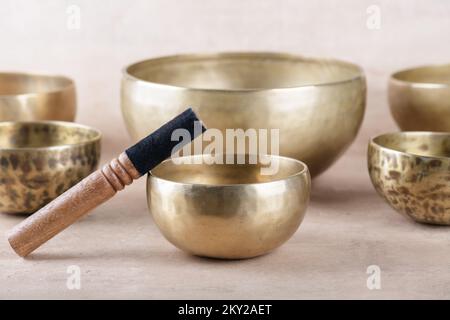 Tibetan singing bowls with sticks used during mantra meditations on beige stone background, close up. Sound healing music instruments for meditation, Stock Photo