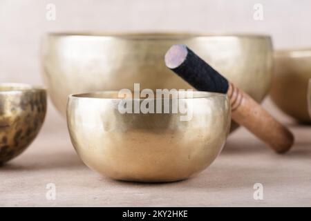 Tibetan singing bowls with sticks used during mantra meditations on beige stone background, close up. Sound healing music instruments for meditation, Stock Photo