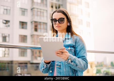 Young business woman millennials in glasses walking Financial District city uses digital tablet in Social networks, Connection, Data, Digital display Stock Photo