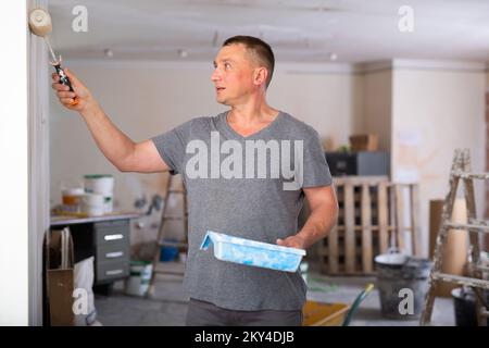 Portrait of positive man painter with paint roller Stock Photo