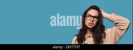 Interesting Offer. Doubtful young woman scratching head and looking aside, wide banner Stock Photo