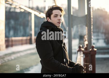 Portrait of a thoughtful hipster guy standing on the bridge Stock Photo