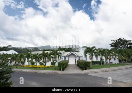 White, one floor white building with palm trees at front and mountains in the background Stock Photo