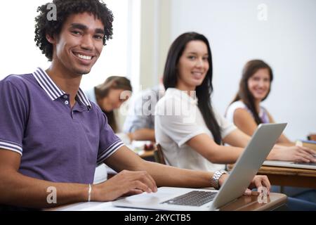 Future software developers...Portrait of a group of smiling university students working on laptops in class. Stock Photo