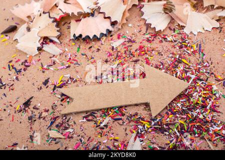 Arrow cut out of paper amid pencil shavings on canvas Stock Photo