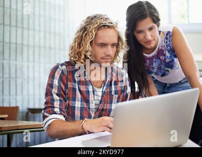 Hes an excellent tutor. Two college students with a laptop in a classroom. Stock Photo
