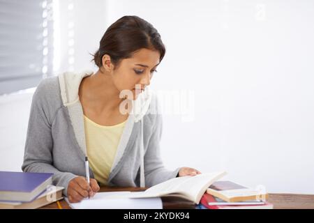 Highlighting the key points. A pretty college student taking notes from her textbook. Stock Photo