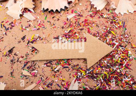 Arrow cut out of paper amid pencil shavings on canvas Stock Photo