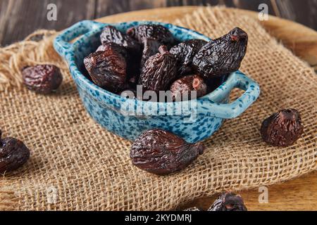 Dried mission figs in glass bowl on burlap and wooden background. Close up Stock Photo