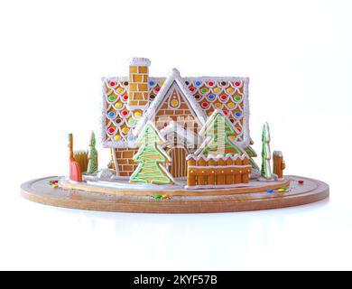 Christmas Gingerbread house in snow. Beautiful gingerbread house with chimney, Сhristmas trees and fence. 3d rendering illustration isolated on white. Stock Photo