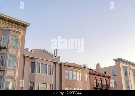 Facade of residential buildings against the dusk sky in San Francisco, CA. There is a house on the right with bricks and railings along with the house Stock Photo