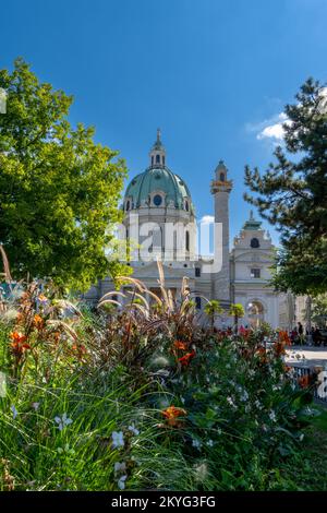 Vienna, Austria - 22 September, 2022: vertical view of the Karlskirche Church in downtown Vienna with colorful flowers in the foreground Stock Photo