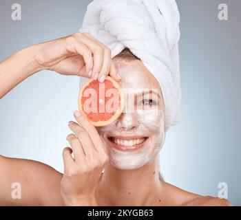 Woman, skincare and mask with grapefruit, smile or happy in studio for wellness, self care or beauty. Model, skin and cream for soft glow with facial Stock Photo