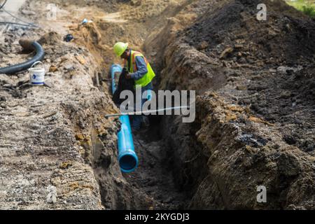 Biloxi, MS, May 6, 2015 - Construction worker from S.J. Construction of Texas checks installation of section of new water line under Nixon Street (near Division Street) in Biloxi, MS. The restoration of Biloxi's water and sewer infrastructure is Mississippi's largest FEMA Public Assistance project related to the Hurricane Katrina recovery effort. Stock Photo