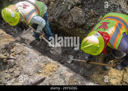 Biloxi, MS, May 6, 2015 - Construction workers from S.J. Construction of Texas dig by hand near a gas line in preparation for the installation of a new water line under Nixon Street (near Division Street) in Biloxi, MS. The restoration of Biloxi's water and sewer infrastructure is Mississippi's largest FEMA Public Assistance project related to the Hurricane Katrina recovery effort. Stock Photo