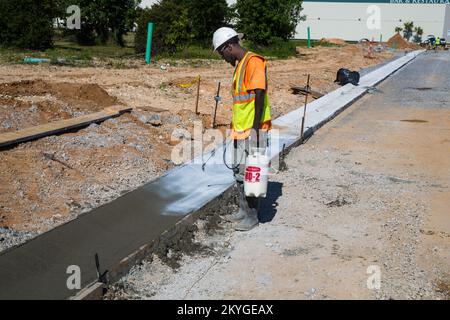 Biloxi, MS, May 6, 2015 - A construction worker from Oscar Renda Contracting finishes concrete preparation related to curb and gutter replacement after the installation of new water and sewer lines under 8th Street in Biloxi, MS. The restoration of Biloxi's water and sewer infrastructure is Mississippi's largest FEMA Public Assistance project related to the Hurricane Katrina recovery effort. Stock Photo