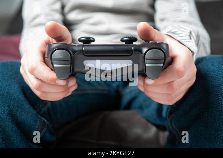 Male hands hold modified plastic joystick closeup, selective focus. Person play videogames. Hold wireless game console. Press buttons on controller by Stock Photo
