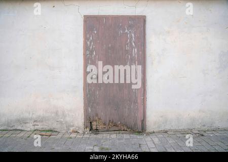 San Antonio, Texas- Weathered wooden door of an abandoned building. Old building exterior with painted concrete wall with cracked lines above the door Stock Photo