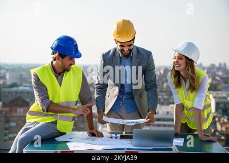Construction concept. Engineers and architects working at construction site with blueprint Stock Photo