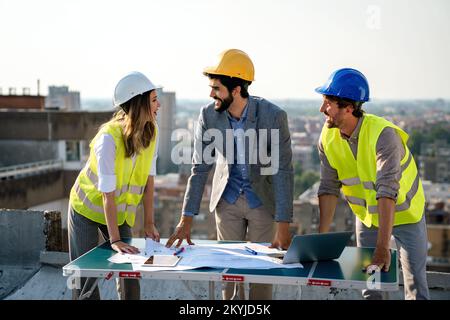 Construction concept. Engineers and architects working at construction site with blueprint Stock Photo