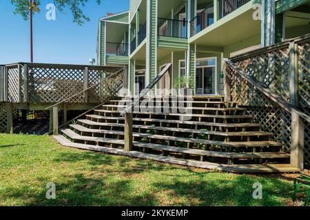 Navarre, Florida- Wide wooden staircase with handrails in the middle. There is a grass at the front of the stairs leading to the veranda of the buildi Stock Photo