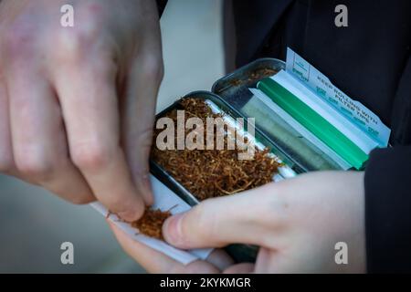 Hand rolling tobacco - person rolling a hand made cigarette Stock Photo