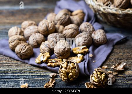 Cracked walnuts and whole walnuts on brown fabric, concept of fresh walnuts, healthy nuts, close-up, selective focus Stock Photo