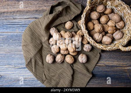 Whole walnuts on wooden rustic background, concept of fresh walnuts in basket, healthy nuts, top view. Stock Photo