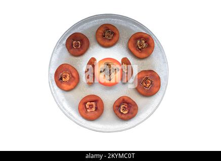 One fresh ripe persimmon fruit with Dried persimmons on round ceramic tray isolated on white background with clipping path. Top view, Selective Focus. Stock Photo