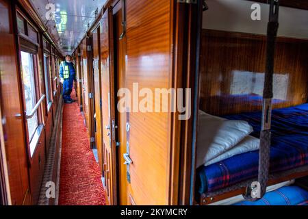 01 December 2022, Mecklenburg-Western Pomerania, Gadebusch: A crane company employee stands in the aisle of the 1941 sleeping car from the legendary Orient Express, which is now parked on the museum track next to the historic train station. Once used between Paris and Istanbul, the 54-ton carriage was lifted by two truck-mounted cranes from the Deutsche Bahn operating track into the museum area during the night. Photo: Jens Büttner/dpa Stock Photo