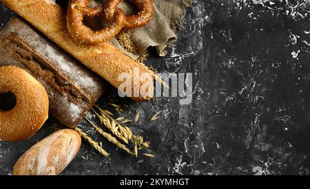 Fresh baked bread assortment on black board background. Top view Stock Photo