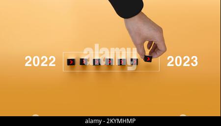 Loading new year 2022 to 2023 with hand putting wood cube in progress bar. Start new year 2023 with goal plan, goal concept, strategy. Stock Photo