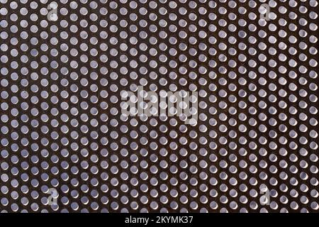 background of perforated rusty metal wall with dots, stucco wall behind Stock Photo