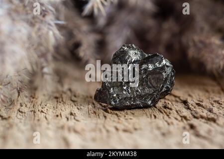 Natural Black Hard Coal Rock Sample on Wooden Background. Brittle Anthracite Shale for Power Production Stock Photo