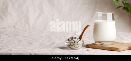 sesame seed milk in glass on textile background with plant. copy space. Raw diet meal. Healthy vegetarian food and lifestyle. eco friendly banner Stock Photo