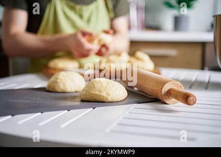 Dough balls preparation concept. Unrecognizable baker working with dough on background, Fresh raw dough. Preparing pizza dough on a table at kitchen at home. High quality image Stock Photo