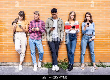 Multicultural people group using smartphone at university college backyard - Millennial friends addicted by mobile smart phone - Technology concept wi Stock Photo