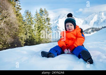 Portrait of a happy young boy sit in snow wear winter outfit Stock Photo