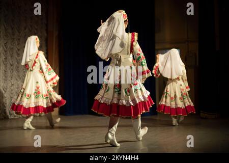 Girls dancing in folk costumes. On stage. Folk dance. Large dresses. Stock Photo