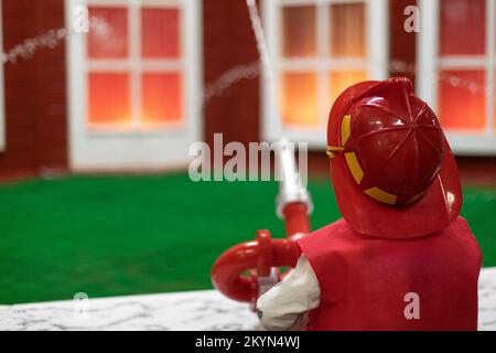 Little fireman. Baby puts out fire. Boy pours water on flames. Burning house. Stock Photo