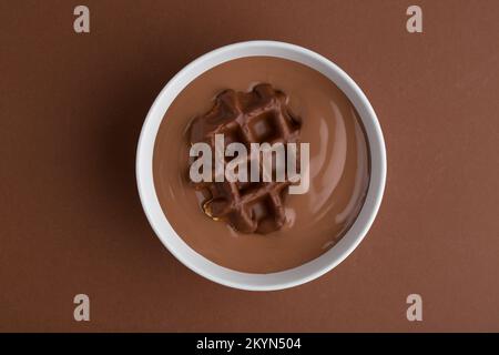Waffles with chocolate topping in chocolatte pudding on brown background.sweet Stock Photo