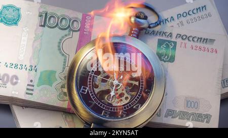 Burning pocket watch with pile of money in wrapper Stock Photo