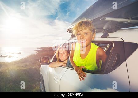 Happy boy and mother smile look from car window at destination Stock Photo